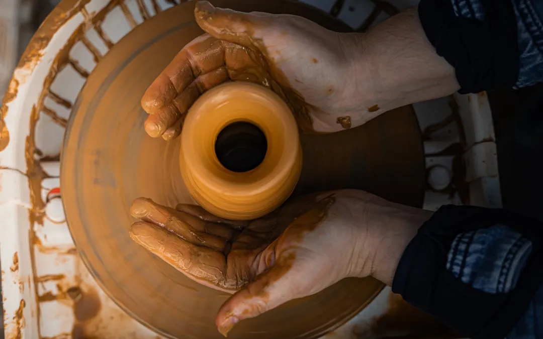 Potter shaping clay on a spinning wheel.
